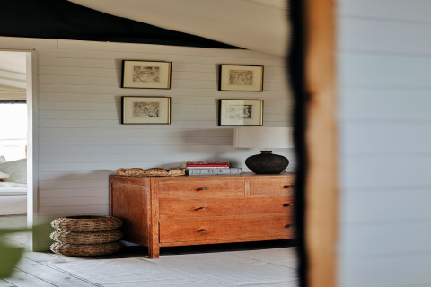 Interieur van de safaritent Owls Nest in het VK met houten ladekast, wandkunst en gevlochten manden.