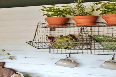 Draadrek met kruidenpotten, artisjokken en mokken in een safaritent genaamd 'Owls Nest' in het Verenigd Koninkrijk.