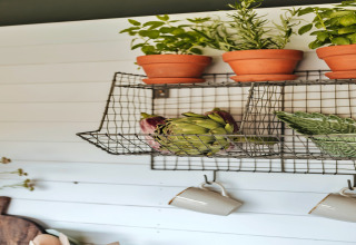 Draadrek met kruidenpotten, artisjokken en mokken in een safaritent genaamd 'Owls Nest' in het Verenigd Koninkrijk.