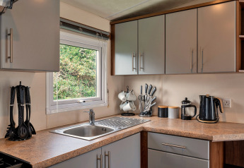 Moderne Küche im Chalet Phoenix Retreat, Großbritannien, mit Geräten, Spüle und Fenster im Grünen.