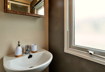 Waschbecken mit Spiegel und Fenster im Phoenix Retreat Chalet in Großbritannien, schlichtes Design.