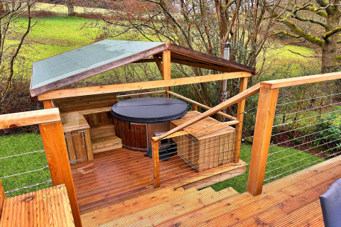 Udendørs terrasse med overdækket boblebad og træmøbler ved Ashdown Luxury Dome i Storbritannien.