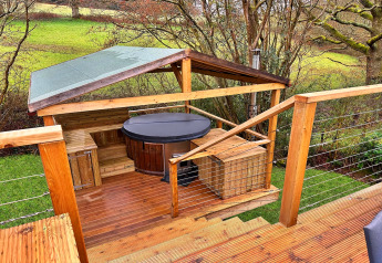 Buitenterras met overdekte hottub en houten banken bij Ashdown Luxury Dome in het Verenigd Koninkrijk.