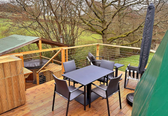 Buitenterras bij Ashdown Luxury Dome in het Verenigd Koninkrijk met zitplaatsen, eettafel en boszicht.