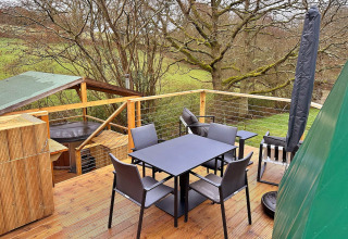 Outdoor deck at Ashdown Luxury Dome in the UK, featuring lounge seating, dining table, and woodland view.
