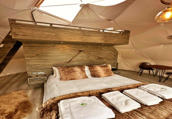 Interieur van de Ashdown Luxury Dome in het VK met loft, comfortabel bed en moderne houten details.