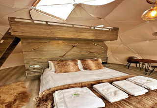 Interior of the Ashdown Luxury Dome in the UK featuring a loft, cozy bed, towels, and elegant decor.