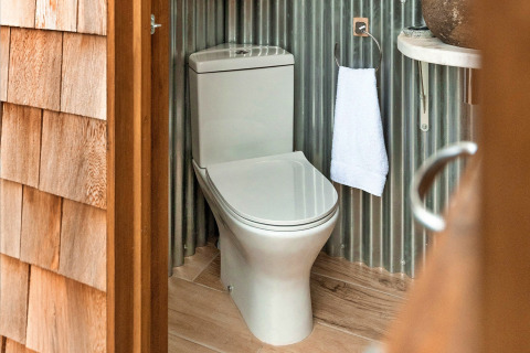 Modern toilet at Ashdown Luxury Dome, United Kingdom, with wood flooring and corrugated metal walls.