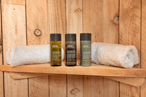 Wooden shelf with two rolled towels and three spa amenity bottles in Ashdown Luxury Dome, United Kingdom.