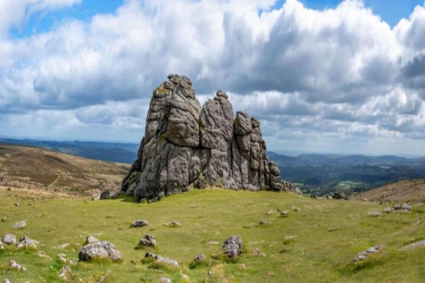 Rocky outcrop on grassy hilltop beneath a dramatic cloudy sky at Ashdown Luxury Dome in the United Kingdom.