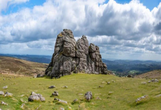 Rocky outcrop on grassy hilltop beneath a dramatic cloudy sky at Ashdown Luxury Dome in the United Kingdom.