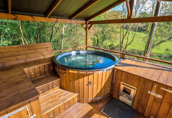 Houten buitenspa met uitzicht op groene natuur bij Wakehurst Luxury Dome in het Verenigd Koninkrijk.