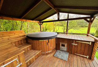 Overdekt houten terras met jacuzzi en landelijke uitzichten bij Wakehurst Luxury Dome, Verenigd Koninkrijk.