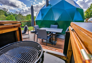 Buitenterras met barbecue en eettafel bij de Wakehurst Luxury Dome, omringd door natuur, Verenigd Koninkrijk.