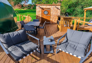 Buitenterras aan de Wakehurst Luxury Dome in het VK, met moderne zetels en barbecuehoek.