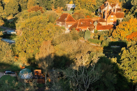 Luchtzicht op Wakehurst Luxury Dome met landelijke huizen te midden van herfstbomen in het Verenigd Koninkrijk.