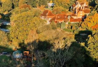 Aerial view of Wakehurst Luxury Dome and rustic houses amid autumn trees in the United Kingdom.
