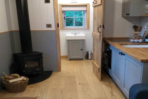 Gezellig interieur van The Bakers Hut stacaravan in het VK met houtkachel, keuken en wastafelgedeelte.