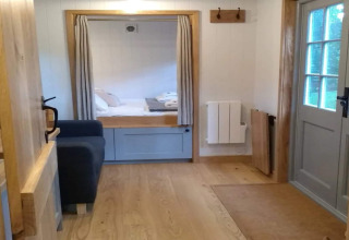 Gezellig interieur met houtaccenten, bank en bed in het The Bakers Hut mobiel huis in het Verenigd Koninkrijk.