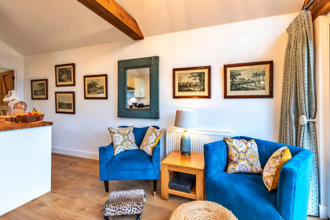 Soggiorno alla South Downs Lodge con poltrone blu, tavolo in legno e quadri appesi alle pareti bianche.