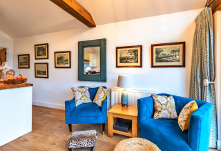 Soggiorno alla South Downs Lodge con poltrone blu, tavolo in legno e quadri appesi alle pareti bianche.