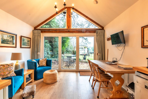 Soggiorno alla South Downs Lodge con ampie vetrate e vista giardino nel Regno Unito.