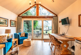 Soggiorno alla South Downs Lodge con ampie vetrate e vista giardino nel Regno Unito.