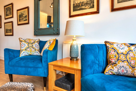 Soggiorno elegante al South Downs Lodge con poltrone blu, cuscini decorati e quadri alle pareti.