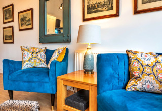 Soggiorno elegante al South Downs Lodge con poltrone blu, cuscini decorati e quadri alle pareti.