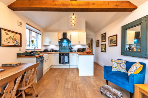 Accogliente zona cucina e soggiorno open space al South Downs Lodge, con arredi moderni e travi in legno.