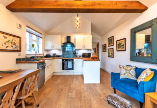 Accogliente zona cucina e soggiorno open space al South Downs Lodge, con arredi moderni e travi in legno.