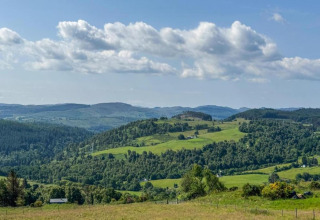 Groene heuvels en bossen onder een blauwe lucht, gezien vanaf The Bakers Hut mobilhome, Verenigd Koninkrijk.