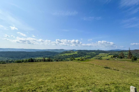 Panoramisch uitzicht op glooiende groene heuvels en velden onder een blauwe lucht bij The Bakers Hut, VK.