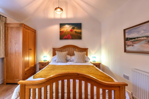 Camera da letto nella casa mobile South Downs Lodge nel Regno Unito con mobili in legno e luce accogliente.