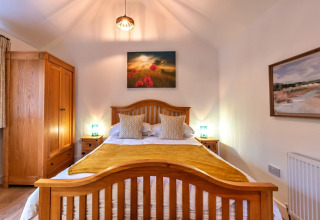 Camera da letto nella casa mobile South Downs Lodge nel Regno Unito con mobili in legno e luce accogliente.