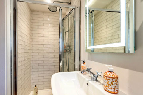 Bagno moderno con doccia, specchio illuminato e lavandino nella casa mobile South Downs Lodge nel Regno Unito.