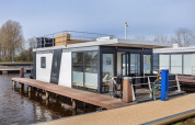 Péniche moderne Agua Dolce amarrée à un quai aux Pays-Bas, avec terrasse et grandes baies vitrées.