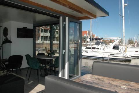 Interior view from houseboat 'Boat' in the Netherlands, showing dining table, sofa, and marina outside.