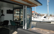 Interior view from houseboat 'Boat' in the Netherlands, showing dining table, sofa, and marina outside.