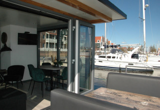 Interior view from houseboat 'Boat' in the Netherlands, showing dining table, sofa, and marina outside.