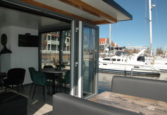 Interior view from houseboat 'Boat' in the Netherlands, showing dining table, sofa, and marina outside.