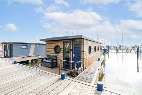 Moderne Hausboot in der Volendam Marina, festgemacht am Steg mit Sitzbereich und Rundfenstern.