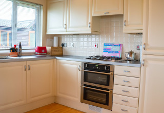 Moderne keuken bij Whitsand Bay Lodge, VK, met witte kasten, gaskookplaat, oven en raam met uitzicht.