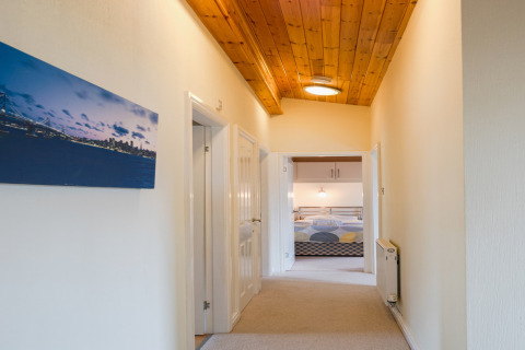 Gang in Whitsand Bay Lodge, Verenigd Koninkrijk, met houten plafond en uitzicht op een slaapkamer.