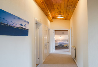 Gang in Whitsand Bay Lodge, Verenigd Koninkrijk, met houten plafond en uitzicht op een slaapkamer.