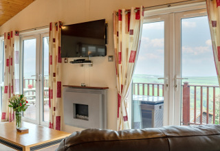 Lichte woonkamer in Whitsand Bay Lodge, VK, met moderne inrichting, tv, open haard en mooi uitzicht.