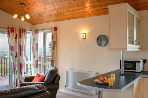 Woonruimte in Whitsand Bay Lodge met leren stoelen, grote ramen, ontbijt en uitzicht op de natuur.