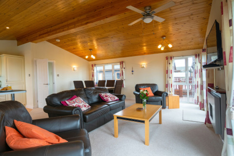 Lichte woonkamer in Whitsand Bay Lodge met leren banken, houten plafond en grote ramen, Verenigd Koninkrijk.