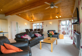 Lichte woonkamer in Whitsand Bay Lodge met leren banken, houten plafond en grote ramen, Verenigd Koninkrijk.