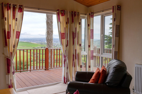 Uitzicht vanuit de woonkamer van Whitsand Bay Lodge, VK, met open gordijnen en groene weilanden.